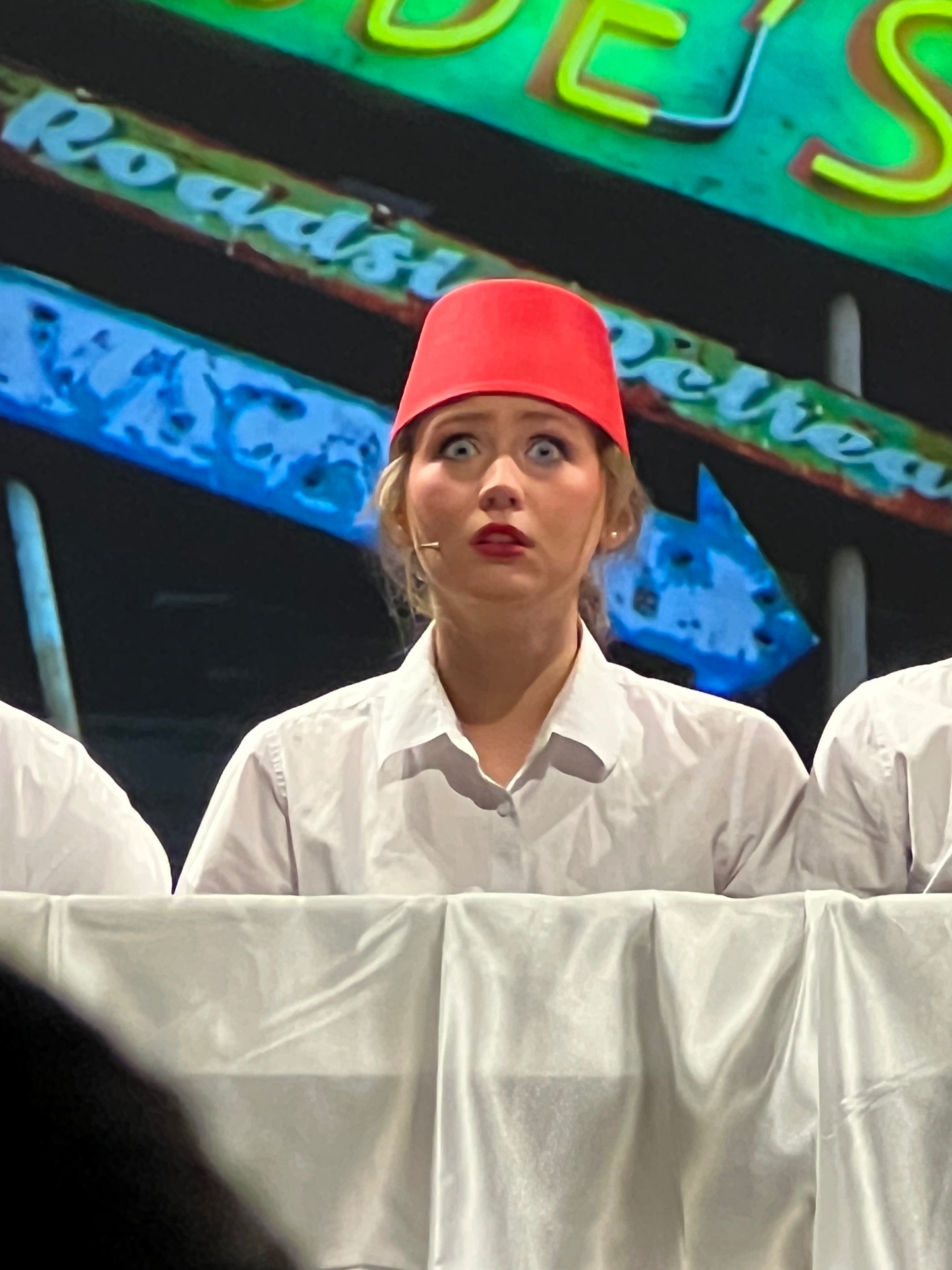 Wide-eyed close-up of Callie Chapman in a red fez and white shirt during Bye Bye Birdie — her Best Facial Expressions moment